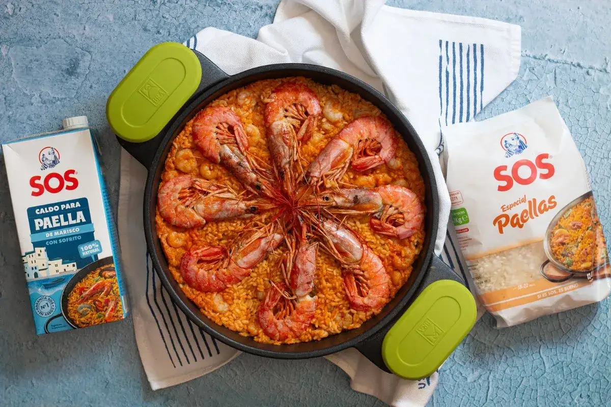 Paella de arroz con gambones, lista para servir. Acompa&ntilde;ada de caldo y arroz especial para paellas SOS.