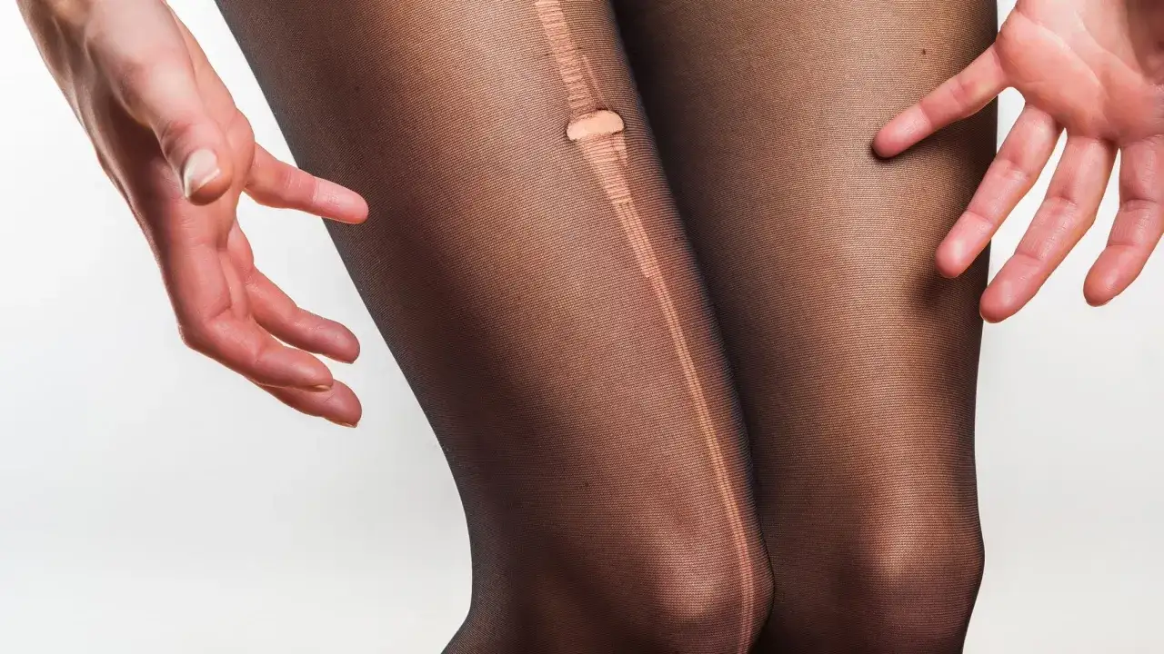 Hände zeigen ein Loch in einer schwarzen Strumpfhose, das zum **Strumpfhose reparieren** einlädt.