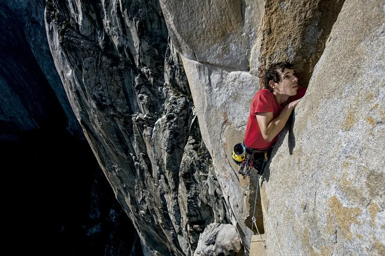 Tom Ballard, escalador, se aferra a una pared de roca imponente, con una caída vertiginosa a su izquierda.