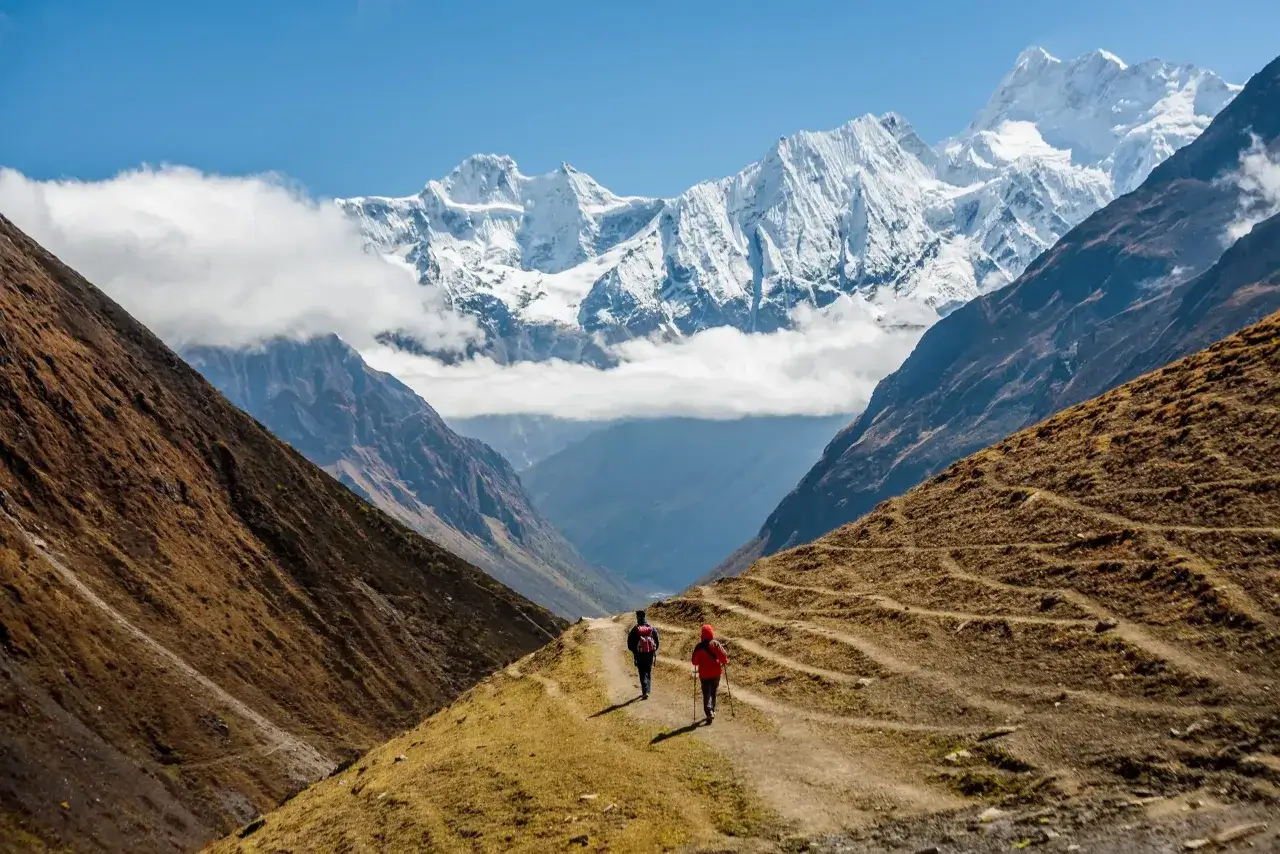 Dwie osoby na szlaku podczas trekking wok&oacute;ł Manaslu. Majestatyczne, ośnieżone szczyty g&oacute;rskie w tle.