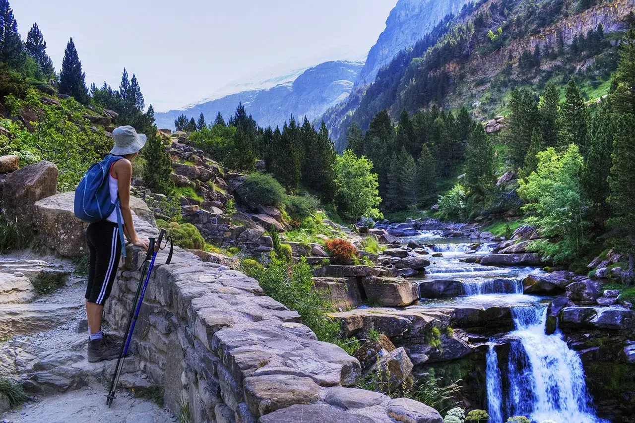 Senderista admira el r&iacute;o y las cascadas en los picos de Huesca.