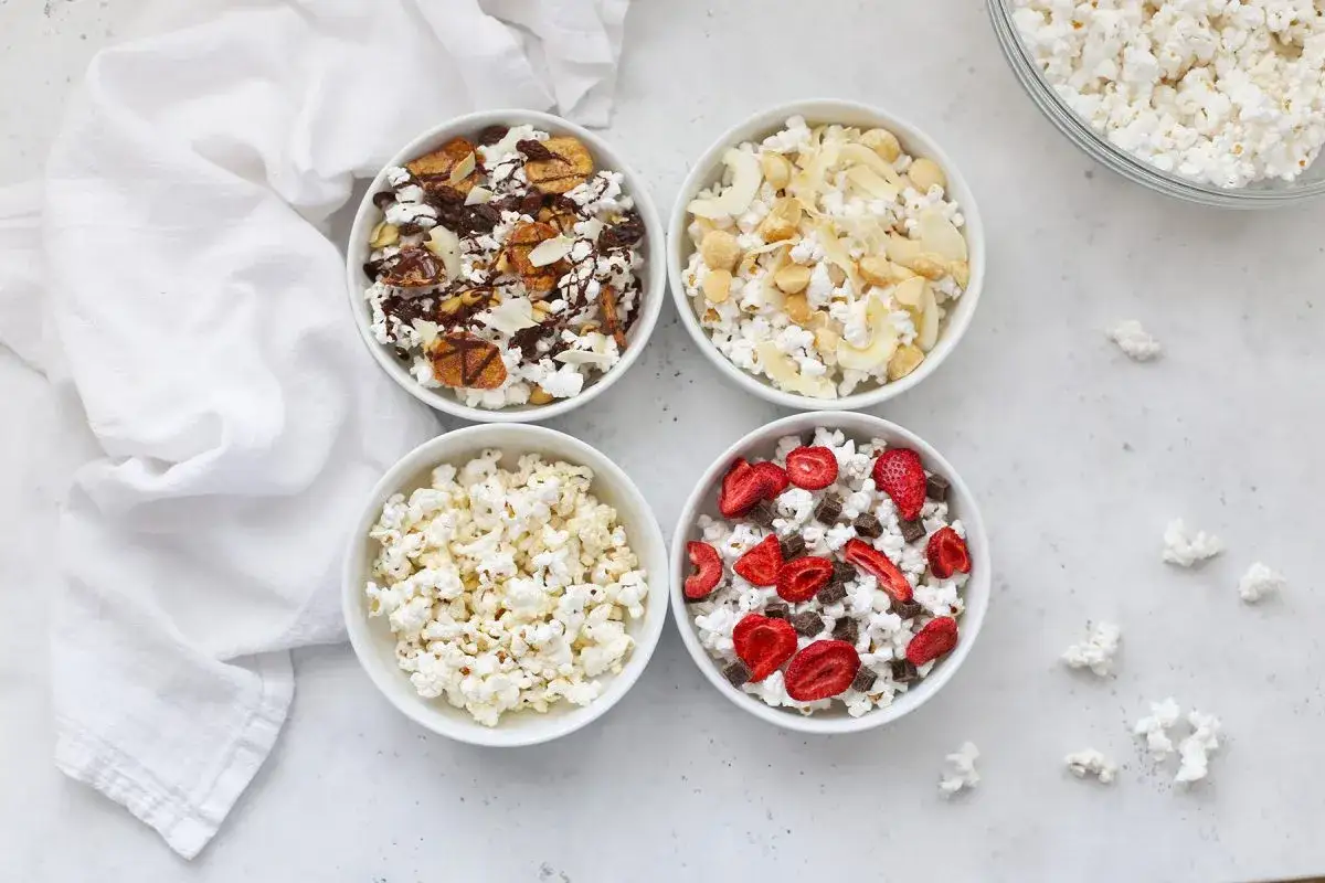 Cztery miseczki popcornu: czysty, z bananem i czekoladą, z orzechami i kokosem, z truskawkami i czekoladą. Czy popcorn jest zdrowy? Zależy od dodatków!