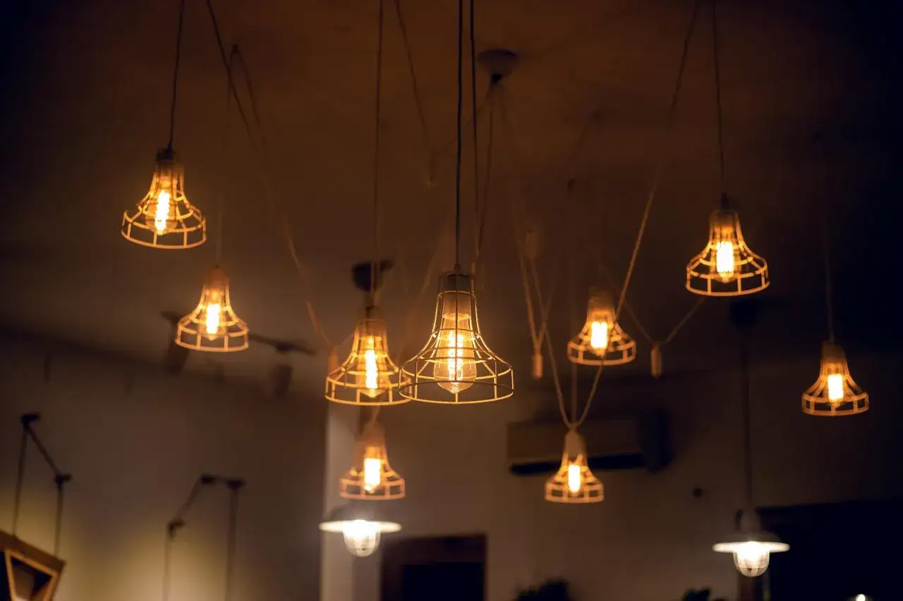 Wiszące lampy z klatkami, emitujące ciepłe światło. Stylowe oświetlenie energooszczędne tworzy przytulną atmosferę.