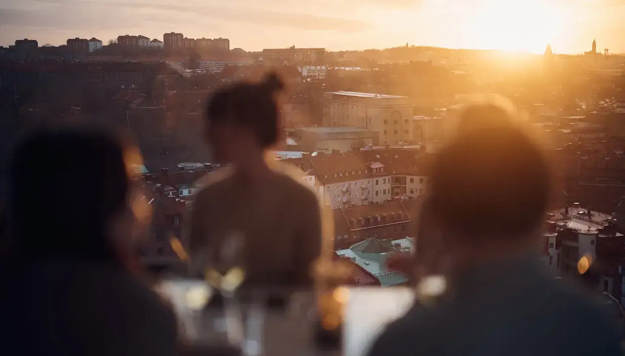 Solnedgång över Göteborg från Gothia Towers Skybar. Vänner njuter av utsikten och varandras sällskap.