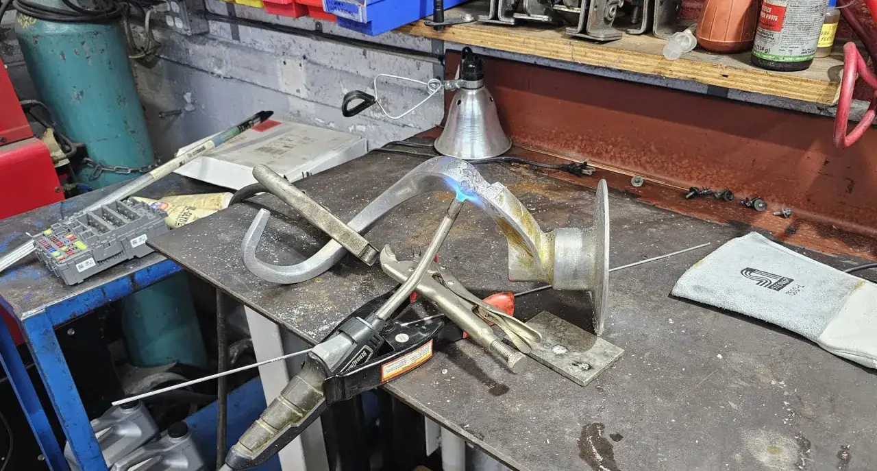 Precyzyjne spawanie aluminium w warsztacie. Widać palnik, uchwyt spawalniczy i elementy aluminiowe.