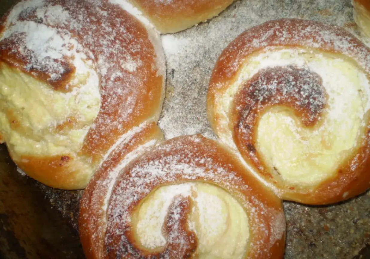 Pyszne, świeżo upieczone drożdż&oacute;wki z budyniem, posypane cukrem pudrem. Idealne na deser lub śniadanie.