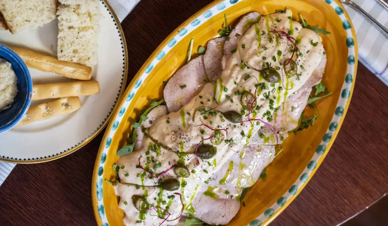 En vacker tallrik med vitello tonnato, tunt skivad kalvfil&eacute; t&auml;ckt med en kr&auml;mig tonfisks&aring;s, kapris och &ouml;rter. Serveras med br&ouml;d och dipp.