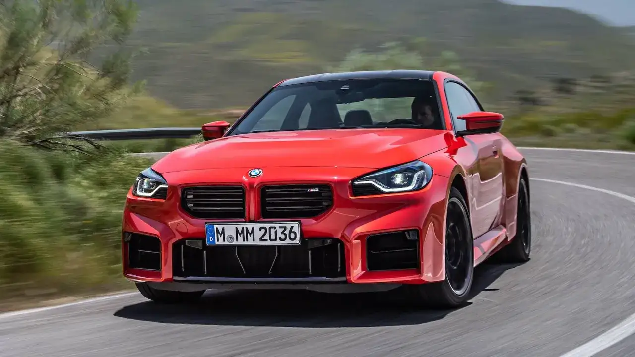 Czerwone BMW M2 Competition pokonuje zakręt na górskiej drodze.
