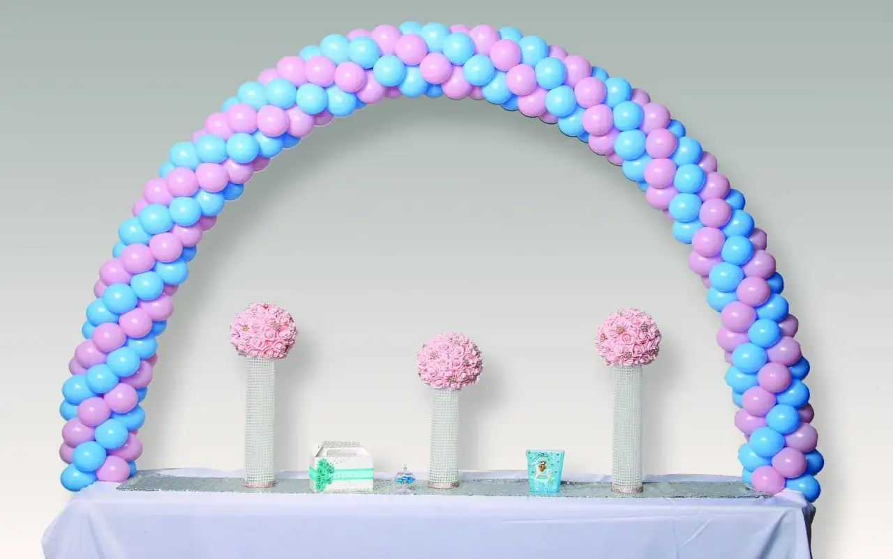 Arco de globos rosa y azul, perfecto para un feliz cumplea&ntilde;os. Tres centros de mesa con flores rosas y detalles brillantes.