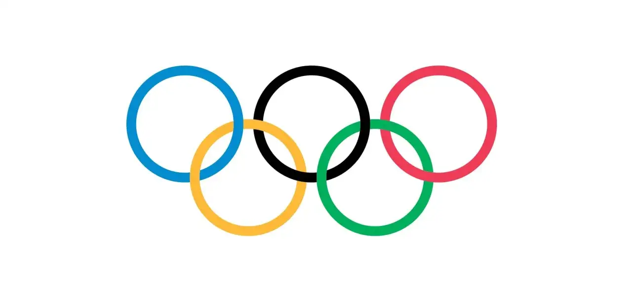 Pięć przeplatających się kół olimpijskich: niebieskie, żółte, czarne, zielone i czerwone, symbolizujące jedność i sportową rywalizację.