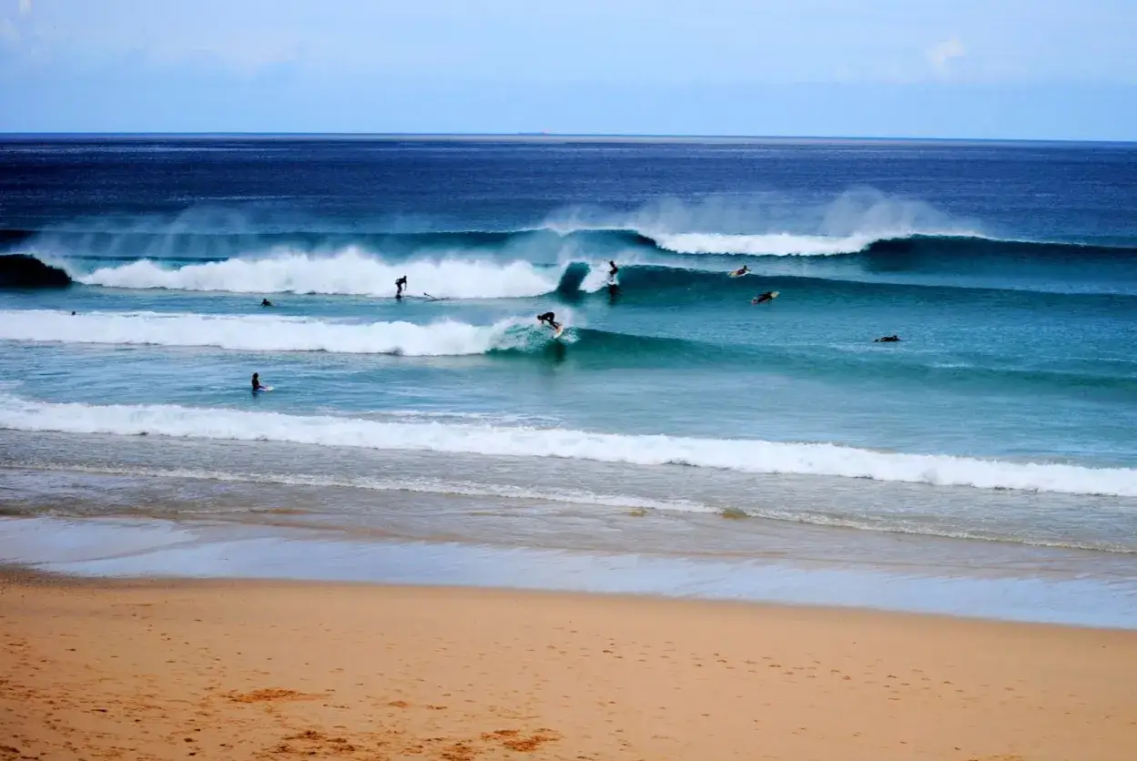 Olas perfectas para surfear en las playas de Galicia. Varios surfistas disfrutan de las olas azules y espumosas.