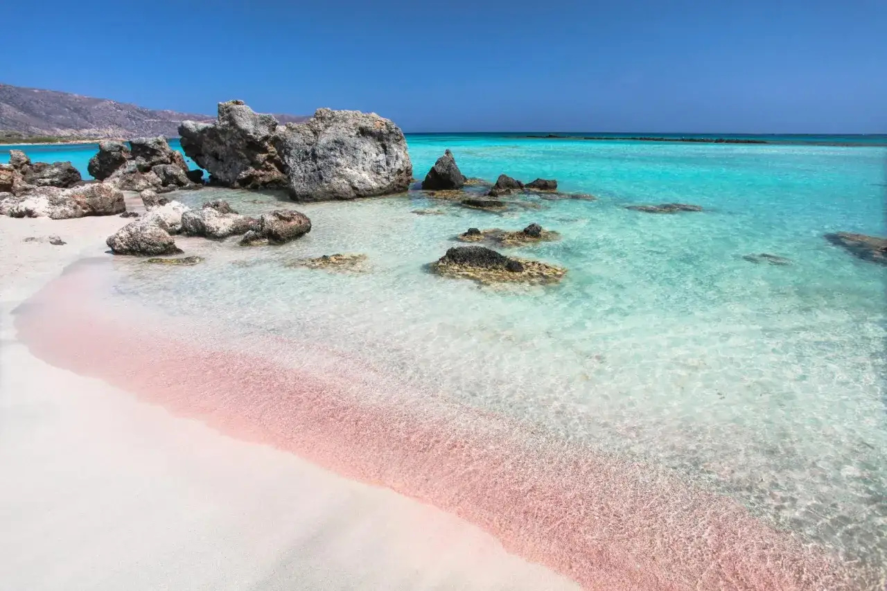 En magisk rosa strand på Kreta med turkost vatten och klippor.
