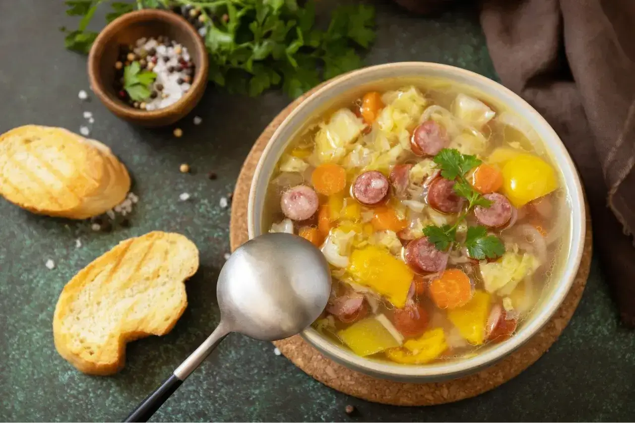 Aromatyczna zupa z kapusty, kiełbasy i warzyw, podana z chrupiącym pieczywem. Idealne na chłodne dni, to właśnie **dobre zupy domowe**.
