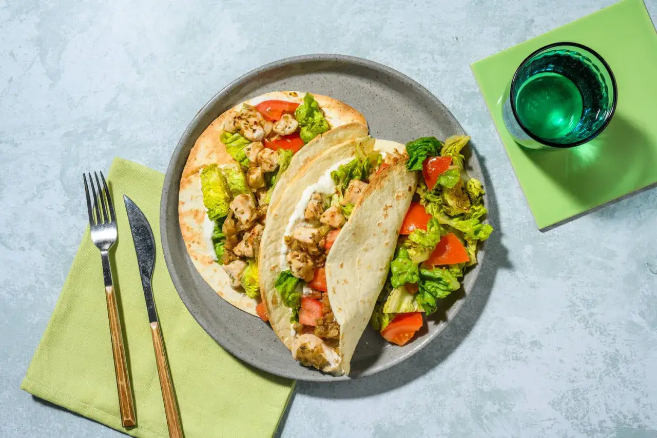 Wraps garnis de poulet, laitue et tomates, une excellente idée repas froid midi. Servi avec un verre d'eau verte.
