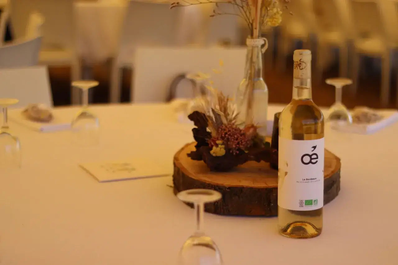 Bouteille de vin blanc sur une table dress&eacute;e, avec un centre de table rustique. Le prix du droit de bouchon est une question &agrave; consid&eacute;rer pour ce repas.