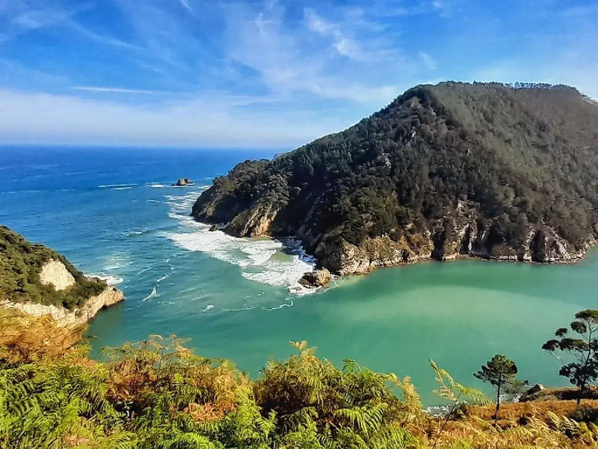 Un paisaje espectacular para tus rutas por el norte de España. Acantilados verdes, mar turquesa y olas rompiendo en la costa.