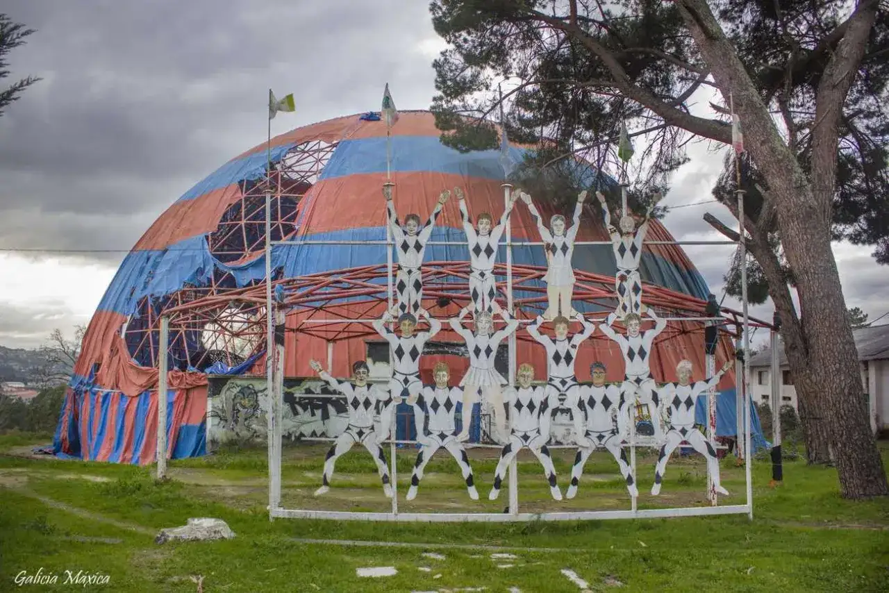 Figuras de circo apiladas frente a una carpa de **Bemposta, Ourense**.