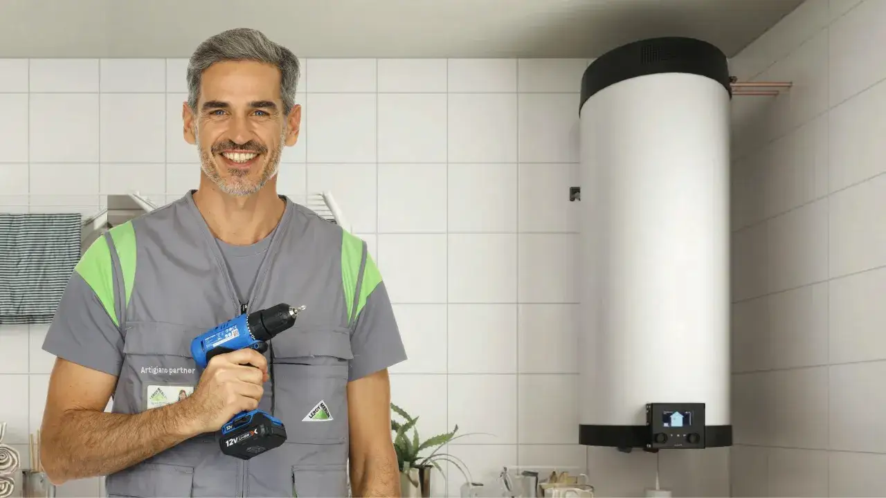 Un tecnico sorridente con un trapano, accanto a uno scaldabagno elettrico. La normativa installazione scaldabagno elettrico è fondamentale per la sicurezza.