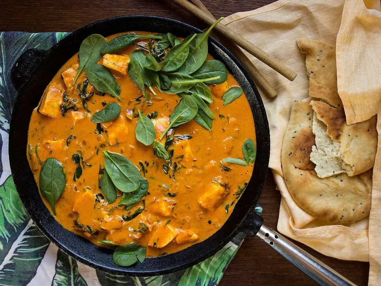 En krämig paneer-rätt med spenat i en orange sås, serverad med naanbröd. Ett utsökt paneer recept.