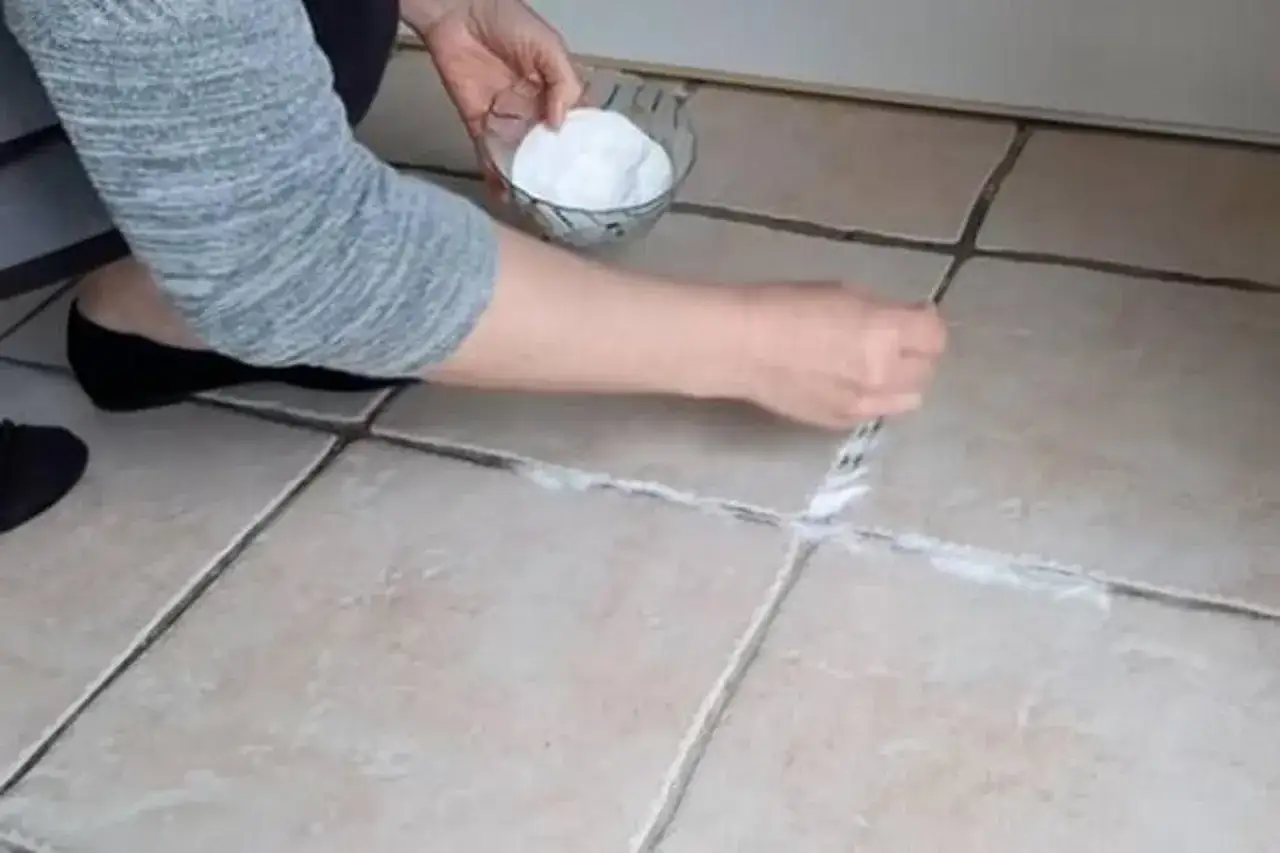 Une personne nettoie les joints de carrelage avec une p&acirc;te blanche, esp&eacute;rant faire dispara&icirc;tre une tache sur carrelage qui ne part pas.