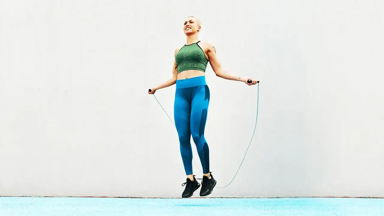 Kobieta w sportowym stroju skacze na skakance. To świetne cardio, które buduje kondycję i siłę.