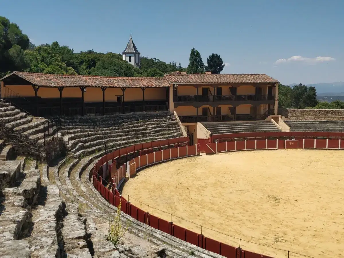 La plaza de toros El Casta&ntilde;ar, con sus gradas de piedra y arena dorada, se alza bajo un cielo azul, lista para la fiesta.