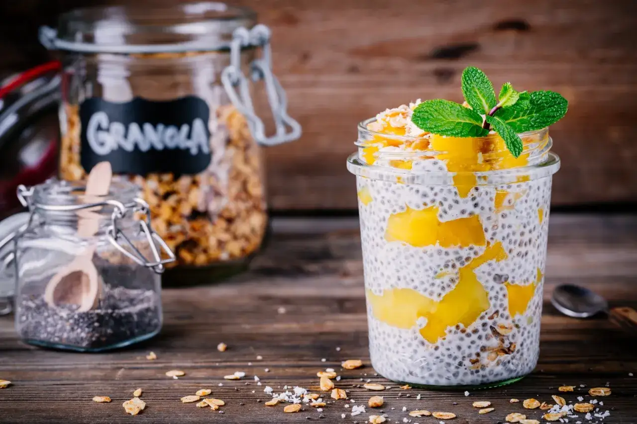 Pudding chia przepis: warstwowy deser z nasionami chia, mango i granolą, udekorowany miętą.