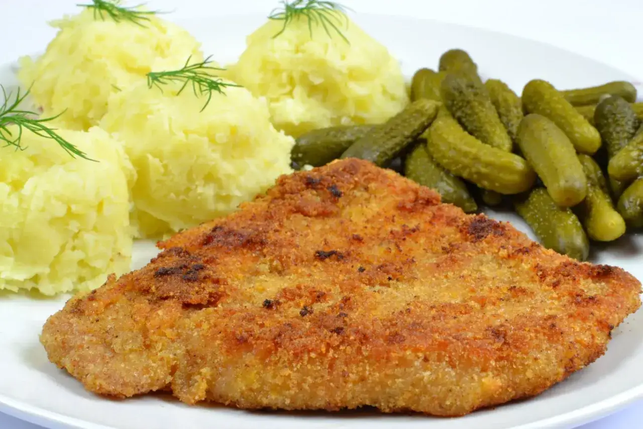 Kotlet schabowy z ziemniakami i ogórkami. Sekret miękkości: rozbij mięso, panieruj i smaż krótko na złoto.