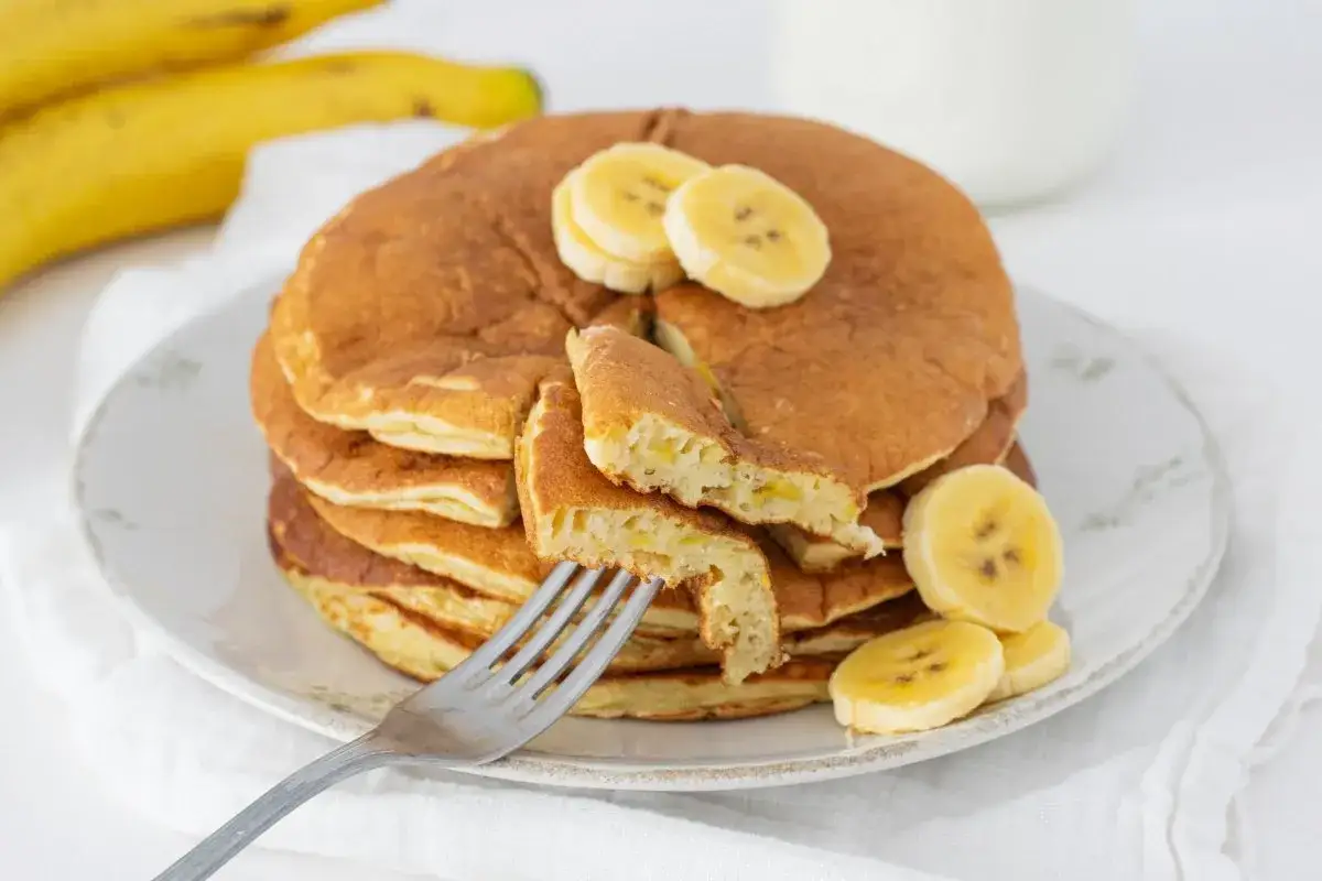 Pila de tortitas esponjosas con trozos de plátano, perfectas para una deliciosa receta tortitas platano.