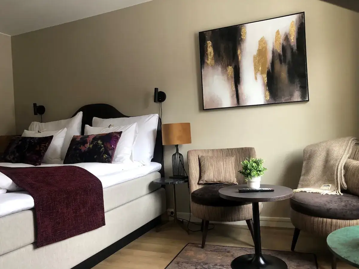 Mysig hotellrum inredning med stor säng, bekväma fåtöljer och modern konst.
