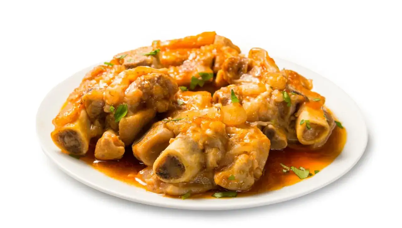 Plato de cap i pota guisado en salsa naranja, con perejil picado.