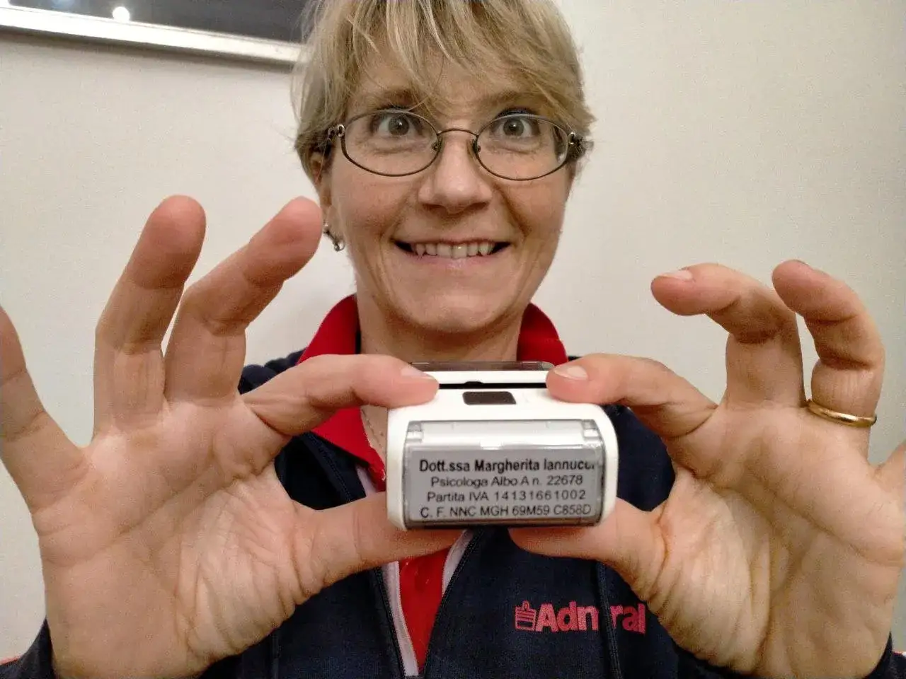 Donna sorridente mostra un timbro con i dati di una psicologa: 