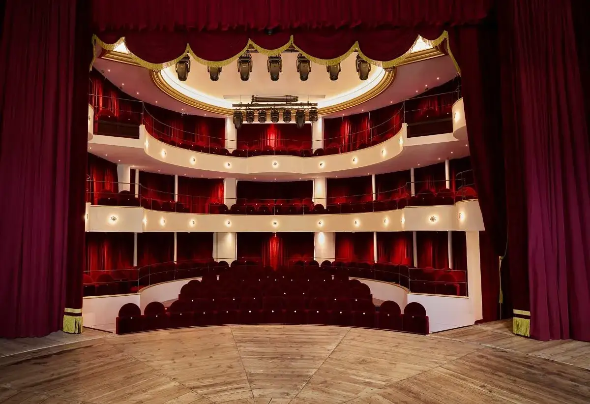 Interno di un teatro con velluti rossi e palchi vuoti. Il palco è pronto per uno spettacolo, ma il teatro cometa off, in attesa del pubblico.