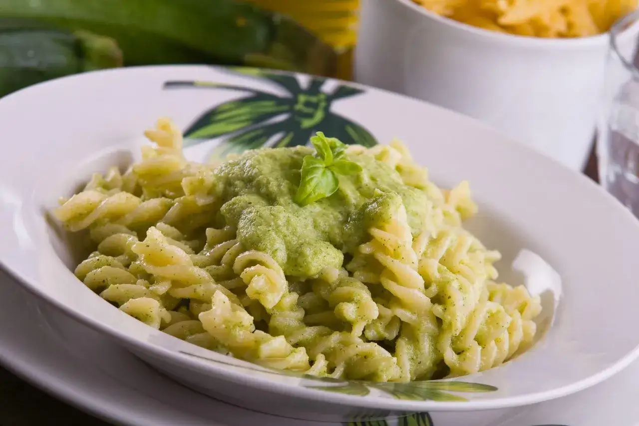 Fusilli z kremowym, zielonym sosem z cukinii, udekorowane listkiem bazylii. Pyszny sos z cukinii do makaronu.