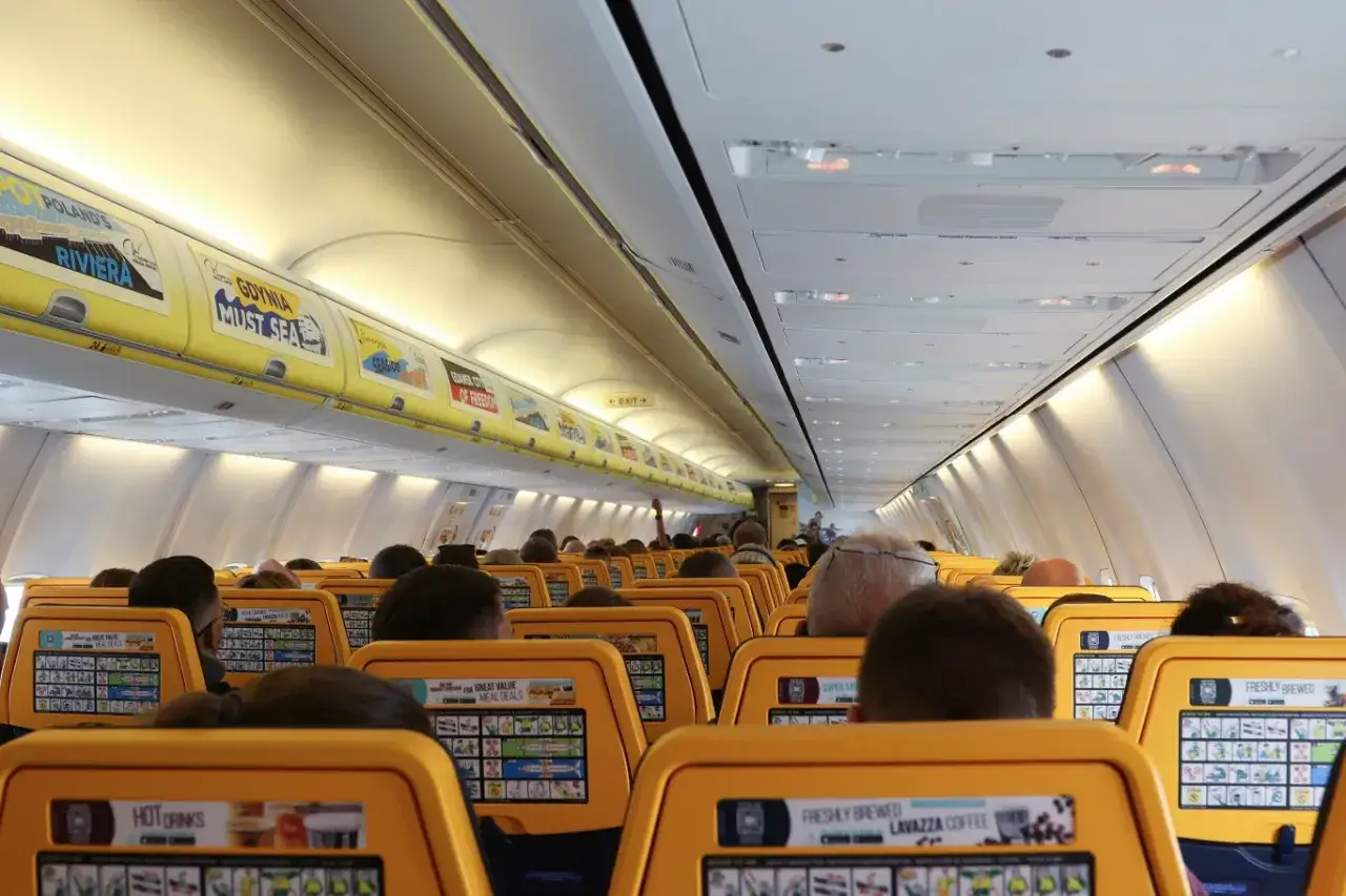 Wnętrze samolotu Ryanair, widok na siedzenia pasażerów. Trudno ocenić, ile osób mieści się w samolocie Ryanair, ale jest tu sporo miejsc.