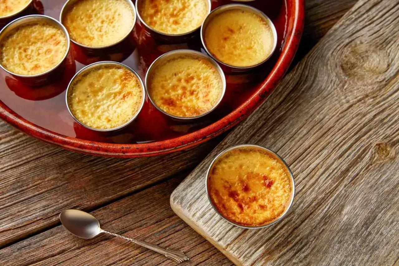 Cr&egrave;me br&ucirc;l&eacute;e dor&eacute;e, r&eacute;sultat d'une cuisson bain-marie au four. Une cuill&egrave;re repose sur le bois.