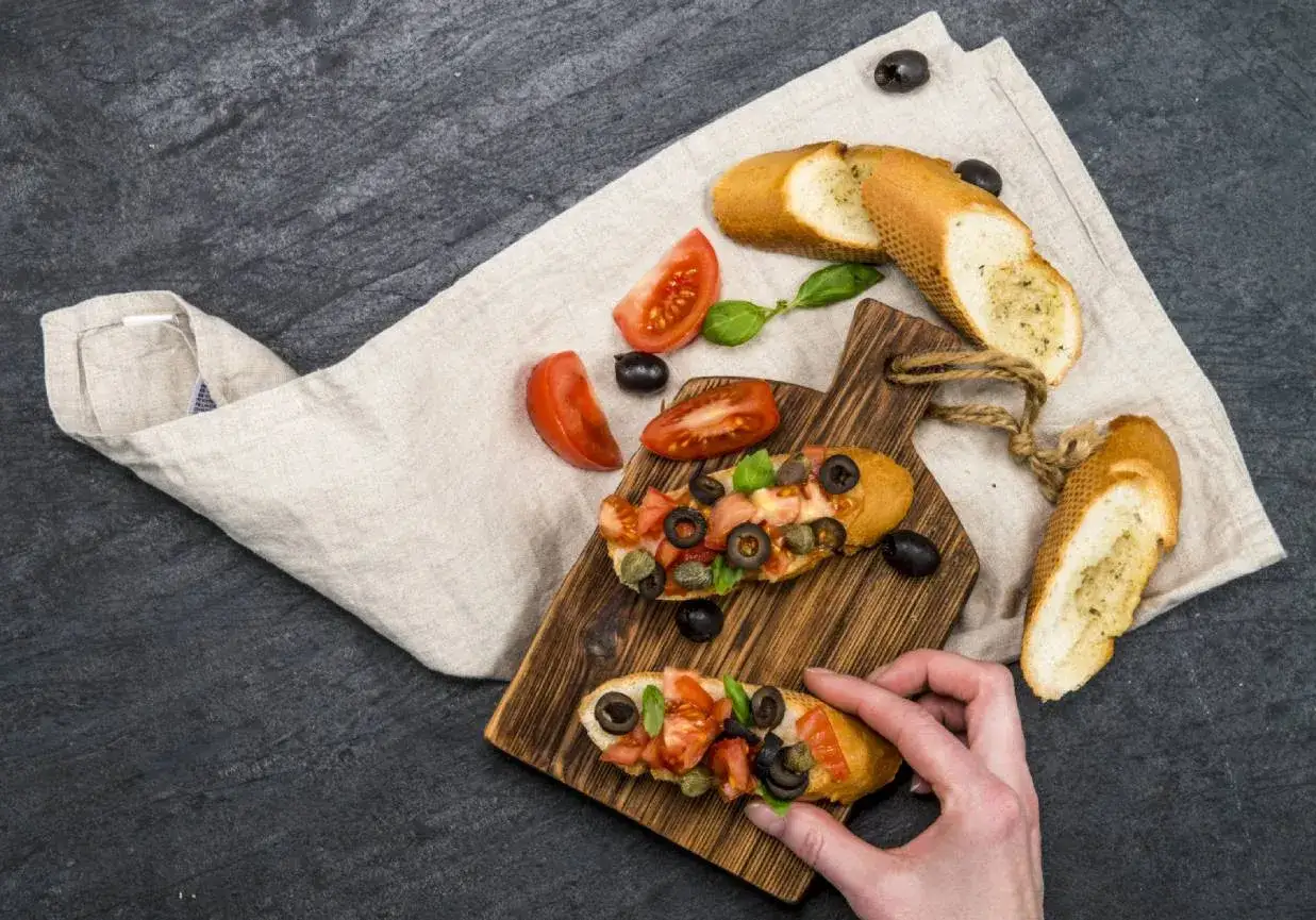 Idealna bruschetta na imprezę: chrupiące pieczywo z pomidorami, oliwkami i bazylią.