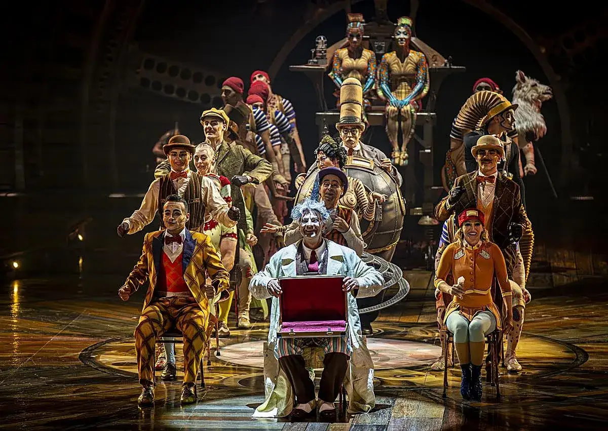 Artistas del circo del sol en Zaragoza, con vestuarios coloridos y maquillaje de fantasía, posan en el escenario.