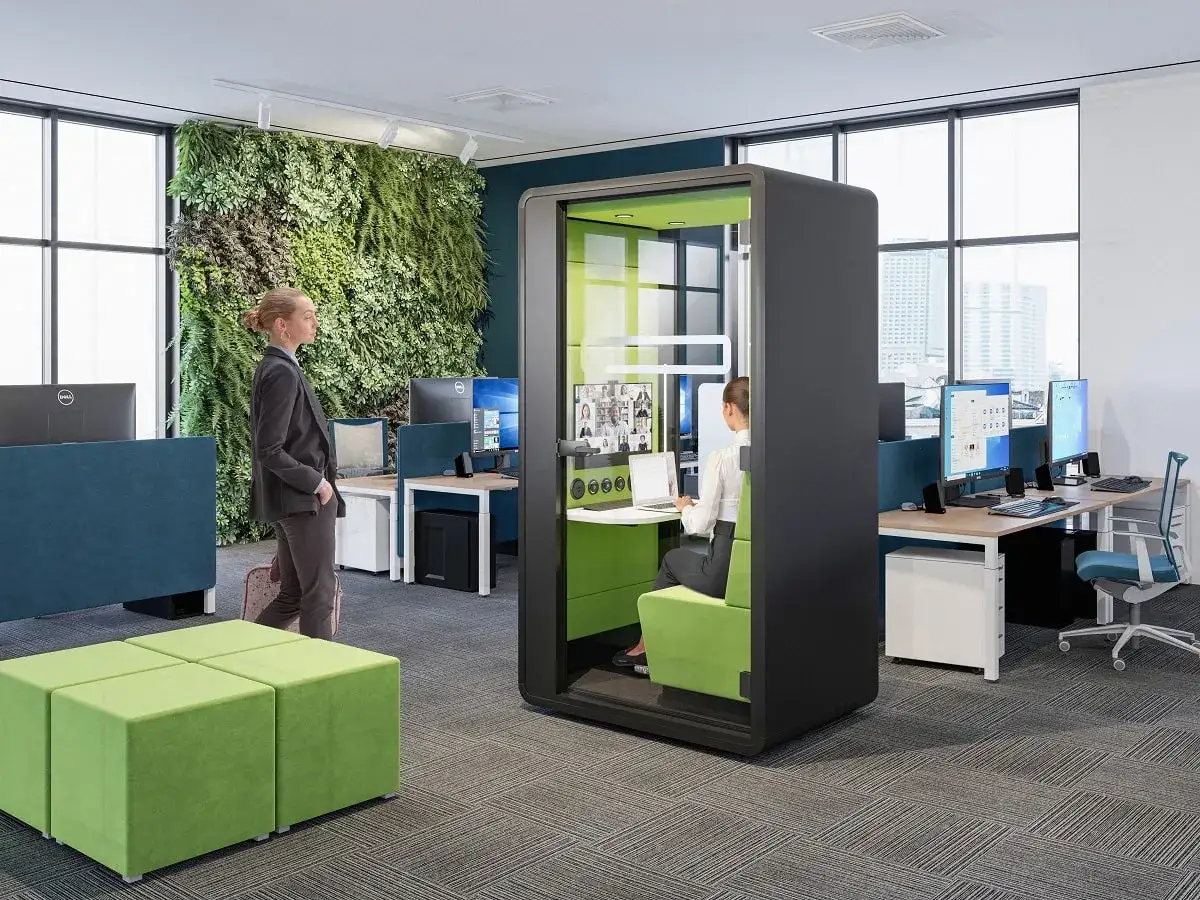Bureau moderne avec mur v&eacute;g&eacute;tal, cabine acoustique pour visioconf&eacute;rence, et postes de travail. Un espace favorisant l'&eacute;quilibre digital.