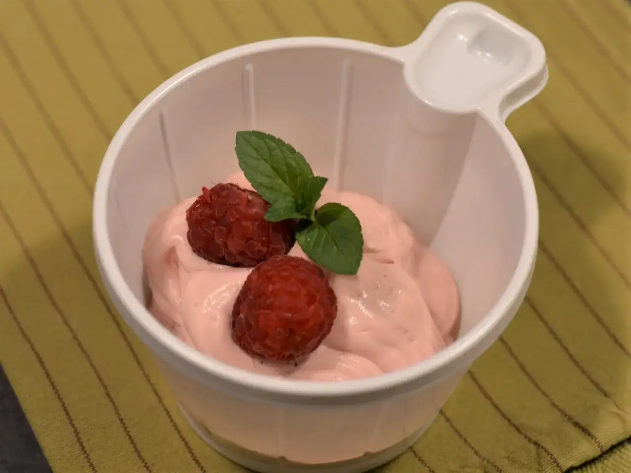 Ljuvlig hallonmousse i vit skål, toppad med färska hallon och mynta. En perfekt dessert!