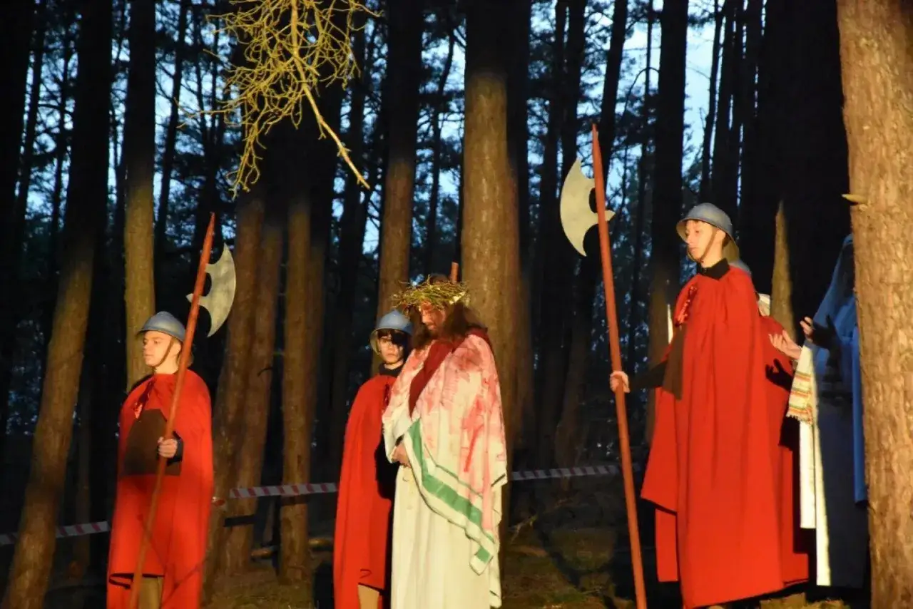 Scena z lasu, gdzie Jezus w koronie cierniowej i żołnierze w czerwonych płaszczach odgrywają misterium. Co to za wydarzenie?