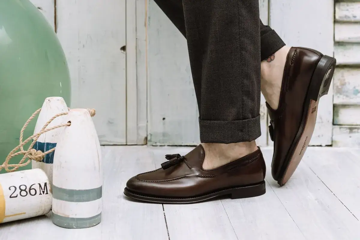 Un uomo indossa un mocassino con abito elegante, abbinato a pantaloni scuri con risvolto.