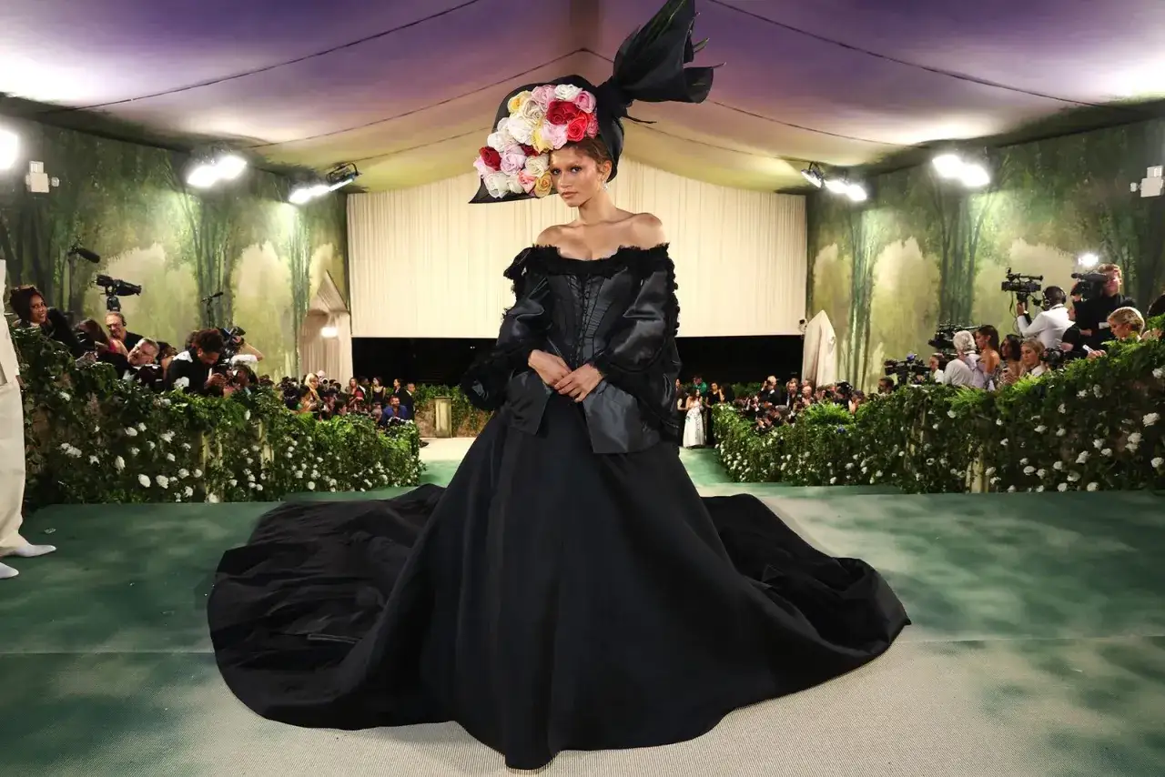 Zendaya stuns at the Met Gala in a dramatic black gown and a voluminous floral headpiece, captivating photographers.