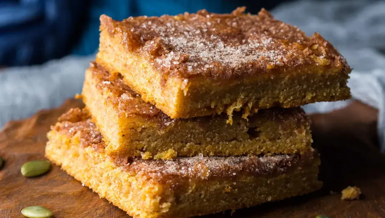 Delicioso brownie de calabaza, con una capa crujiente de azúcar y canela, apilado sobre una tabla de madera.