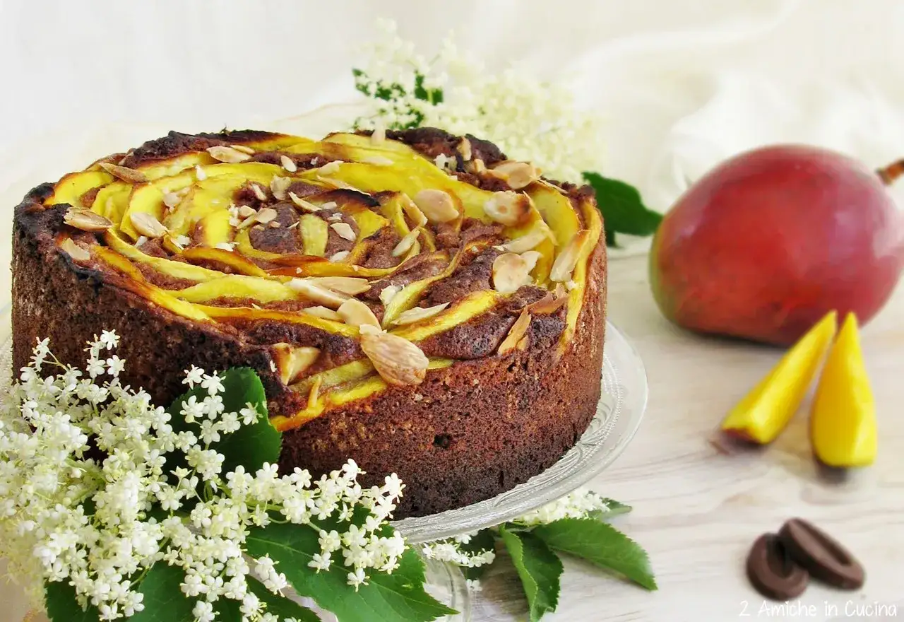 Torta mango e cioccolato con mandorle e fiori di sambuco. Un dolce invitante, perfetto per ogni occasione.