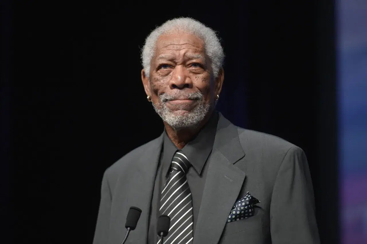 Morgan Freeman, znany z niezapomnianych ról w filmach, w eleganckim garniturze i krawacie, przemawia na scenie.