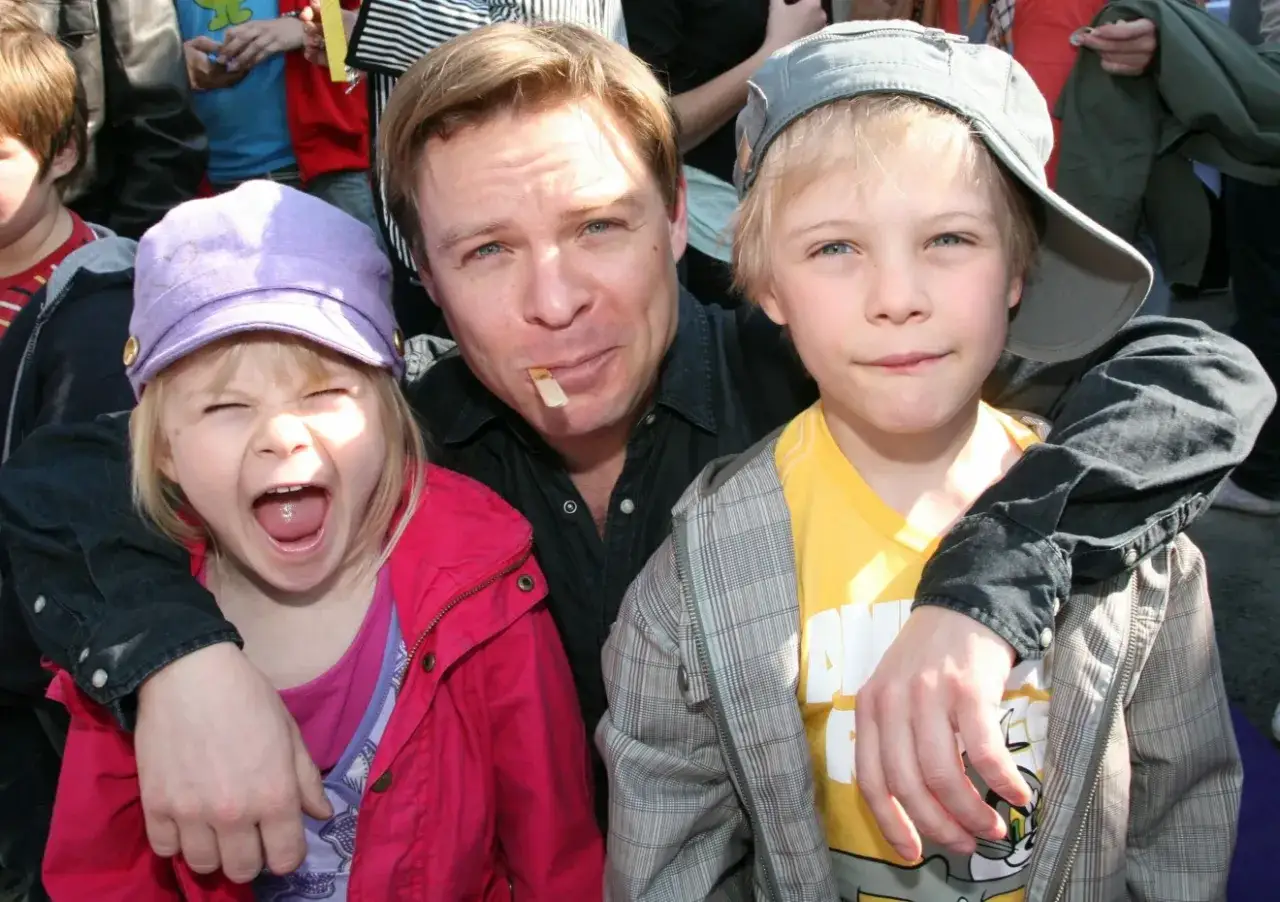 Kasper Sulocki med sina barn. En flicka med lila keps och en pojke med grå keps.