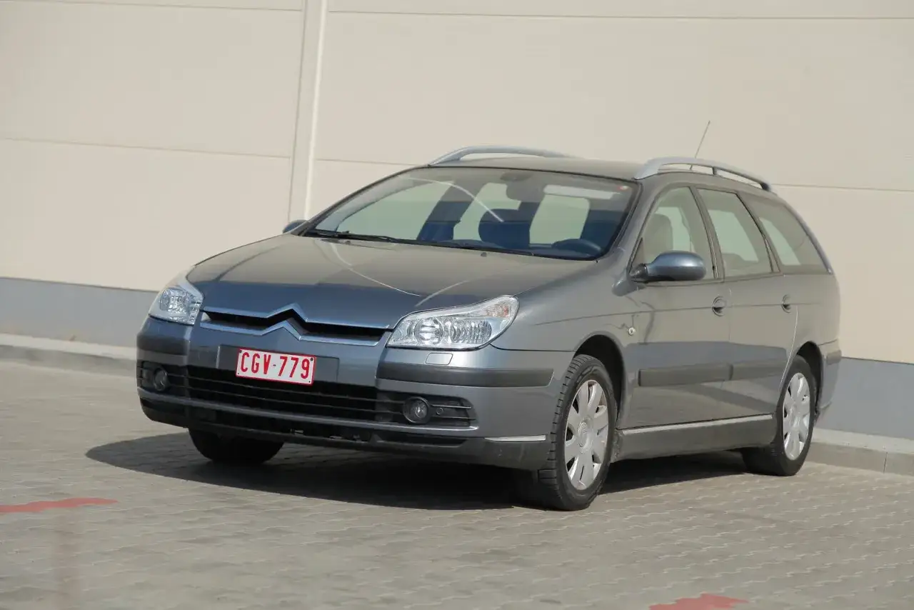Szary Citroen C5 kombi z widocznymi przednimi żarówkami, zaparkowany na kostce brukowej.