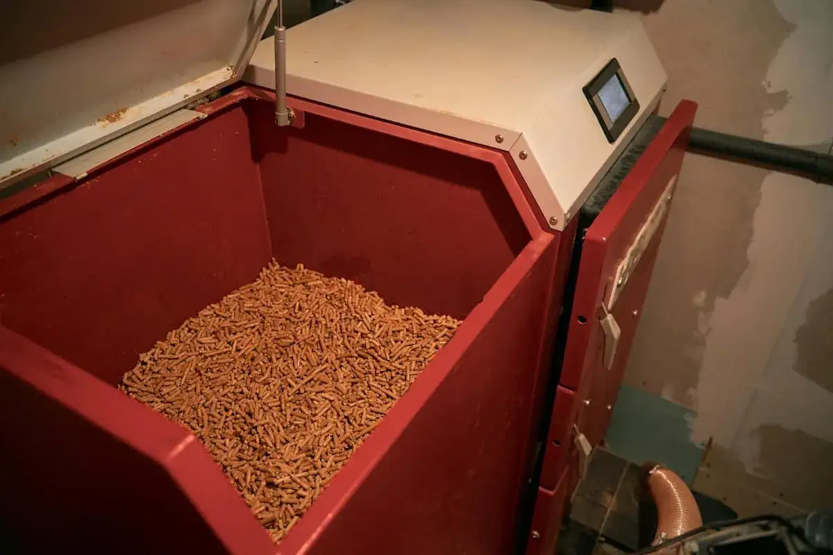 Réservoir rouge rempli de granulés de bois pour une chaudière à granulés. Avis sur ce système de chauffage écologique.