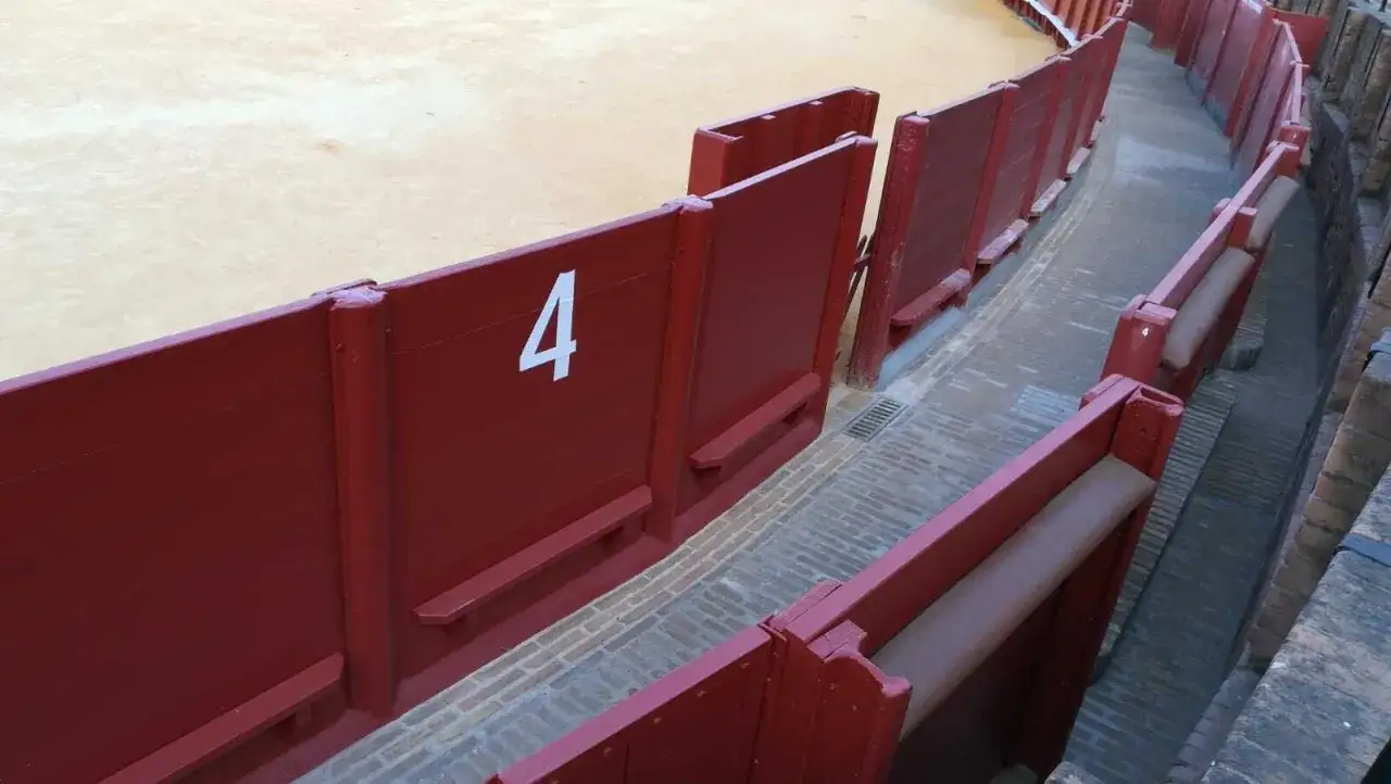 Burladeros rojos numerados en una plaza de toros, listos para la acci&oacute;n.
